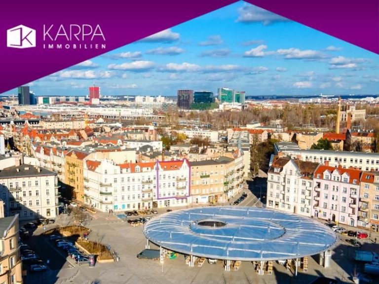 Altersgerechte Apartments Mikrowohnungen Seniorenwohnugen in Hamburg Rahlstedt Helles Wohnzimmer mit Sofa, Esstisch, TV und Blick auf den Garten durch große Fenster.